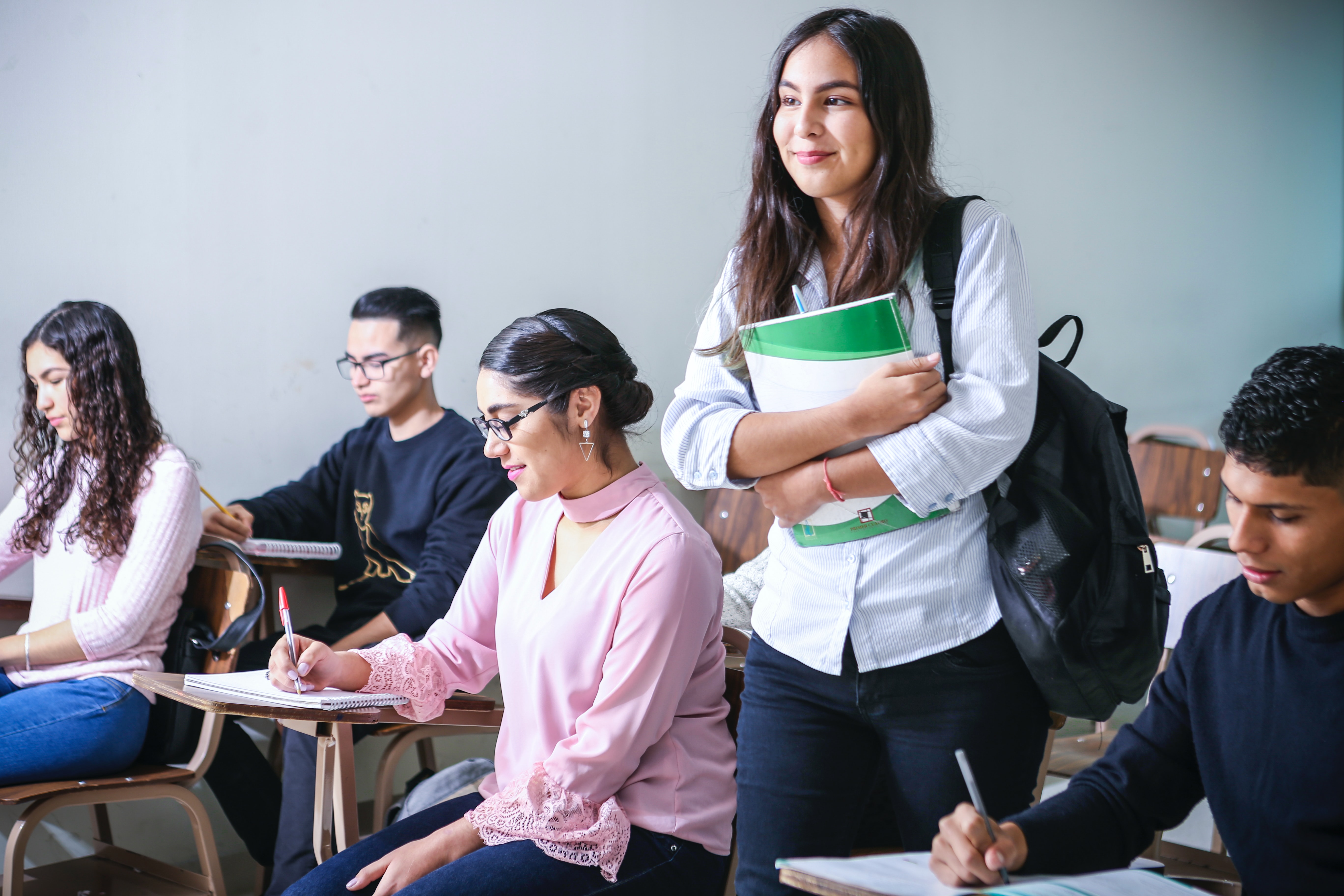 A student proudly standing in the middle of a classroom.